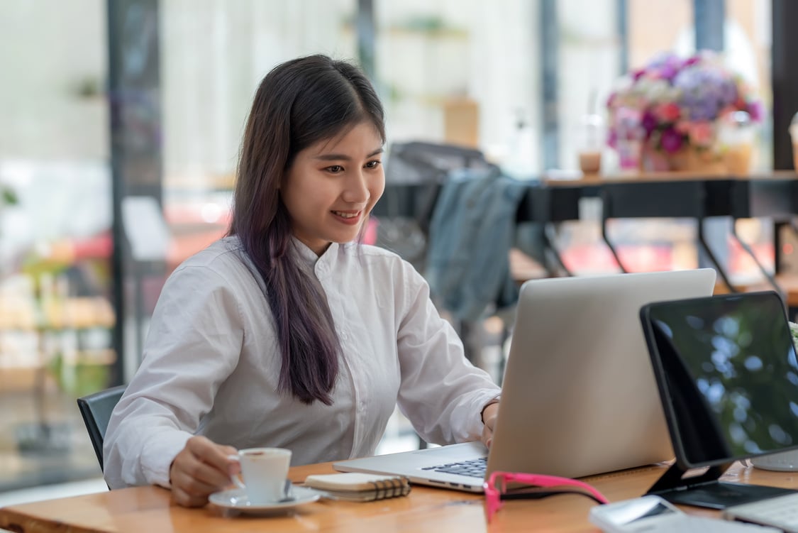 Front View of an Asian Businesswoman Working on a Laptop Holding